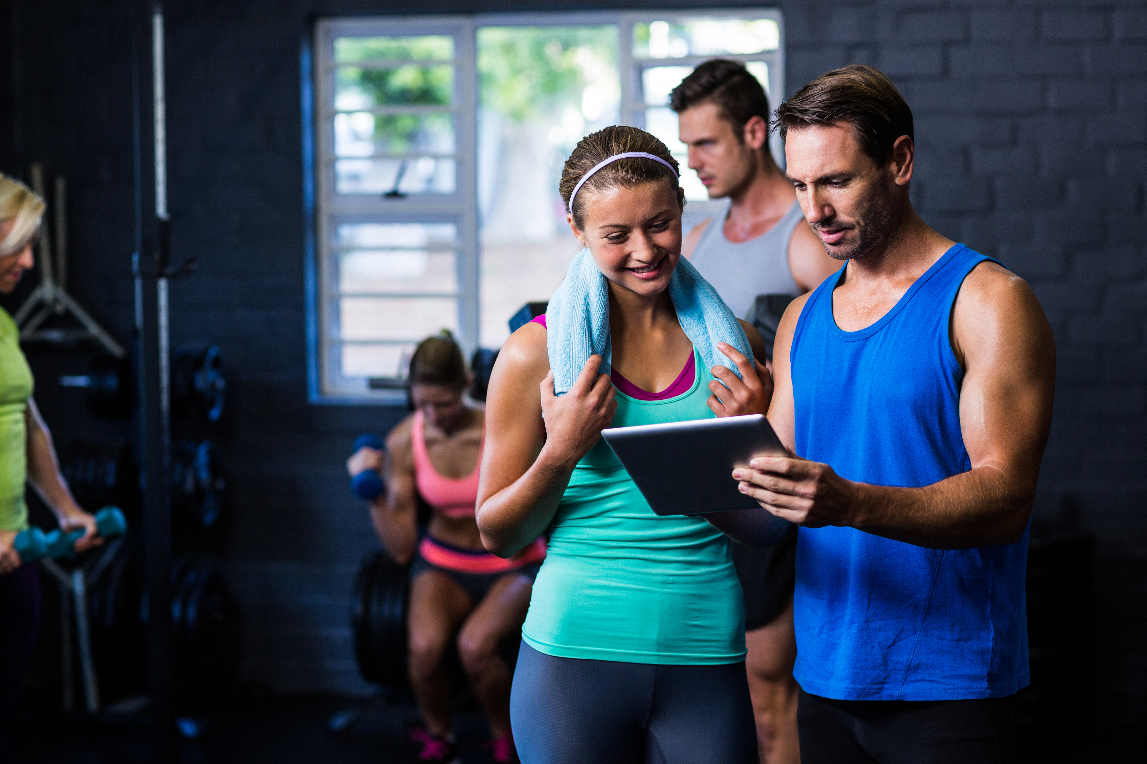 Gym trainer reviewing membership program with a client on tablet